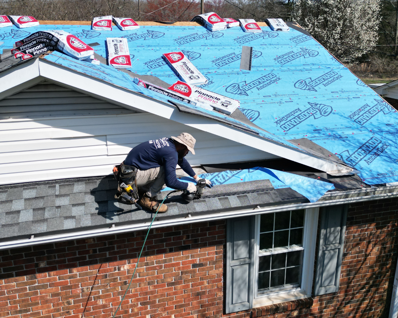 Southern Shingles employee on top of residential roof, nailing down shingles.