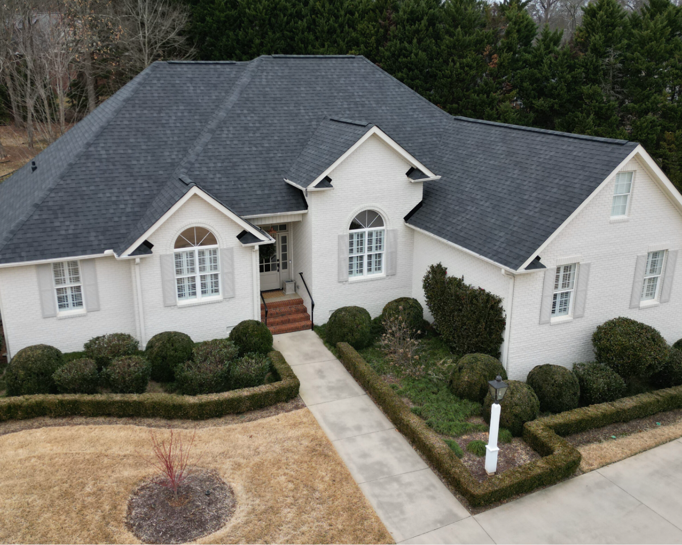 Aerial shot of newly constructed, two story, modern home with white brick and new asphalt shingle roof.