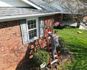 Southern Shingles employee, climbing on ladder to inspect roof.