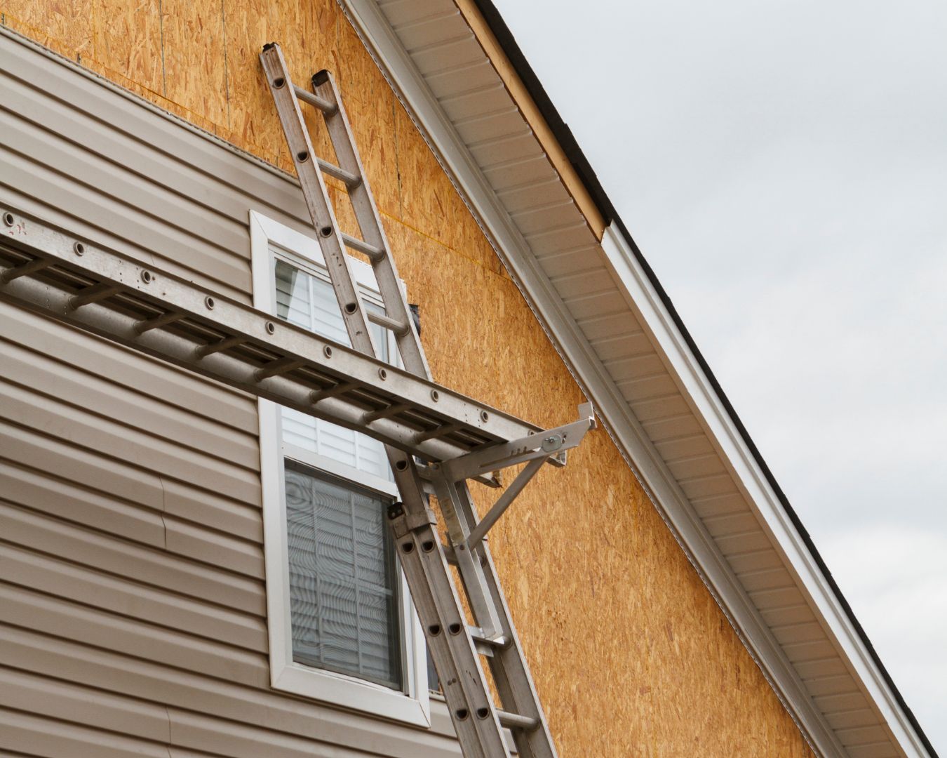 Siding in the process of being installed on residential home. Ladder is propped up against home.