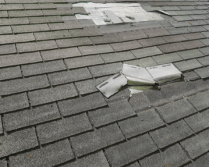 Close up shot of damaged roof with lifted shingles.